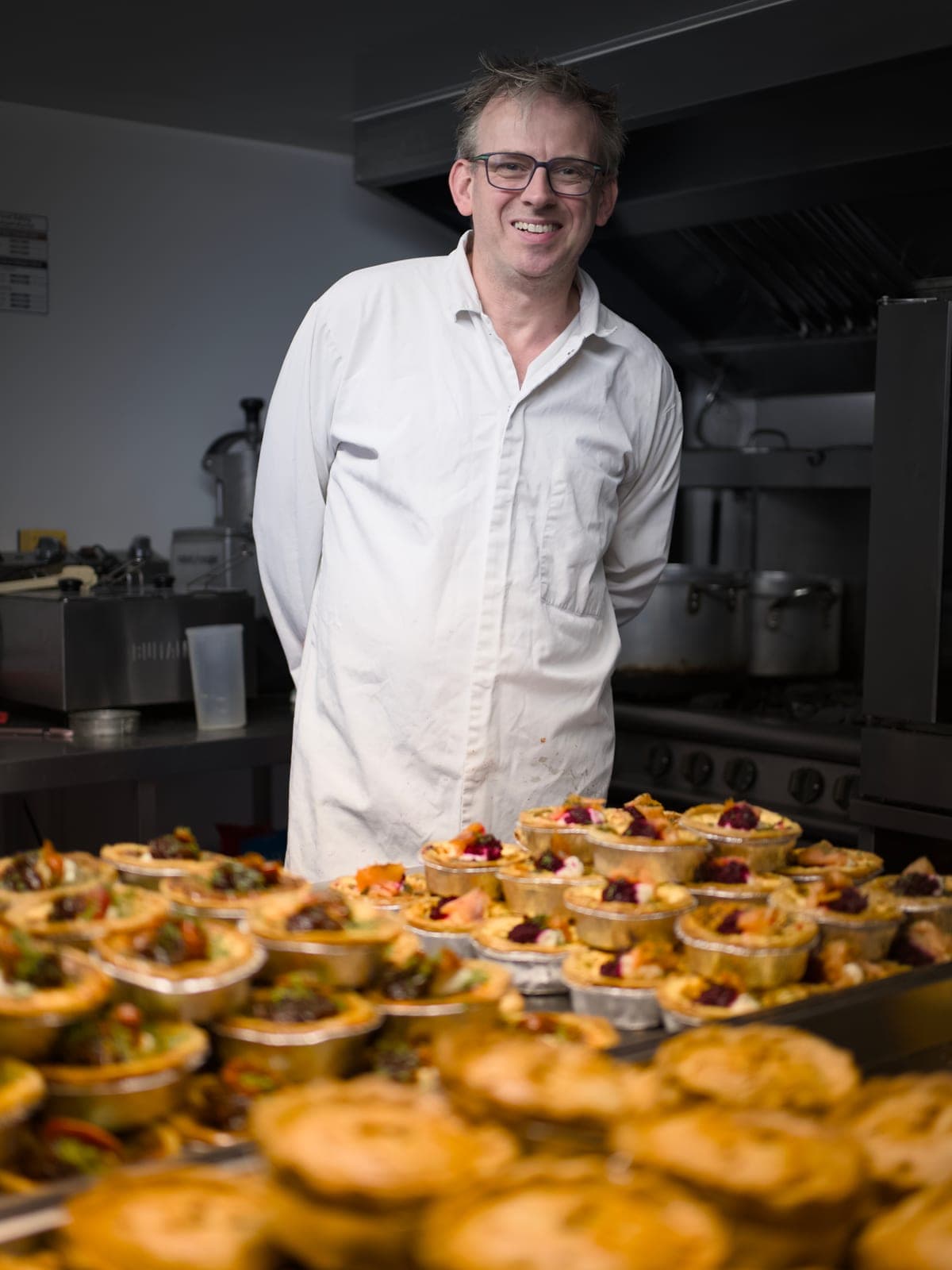 Paul Stretton, founder of Pies, Puds & Tarts, standing behind trays of freshly baked pies